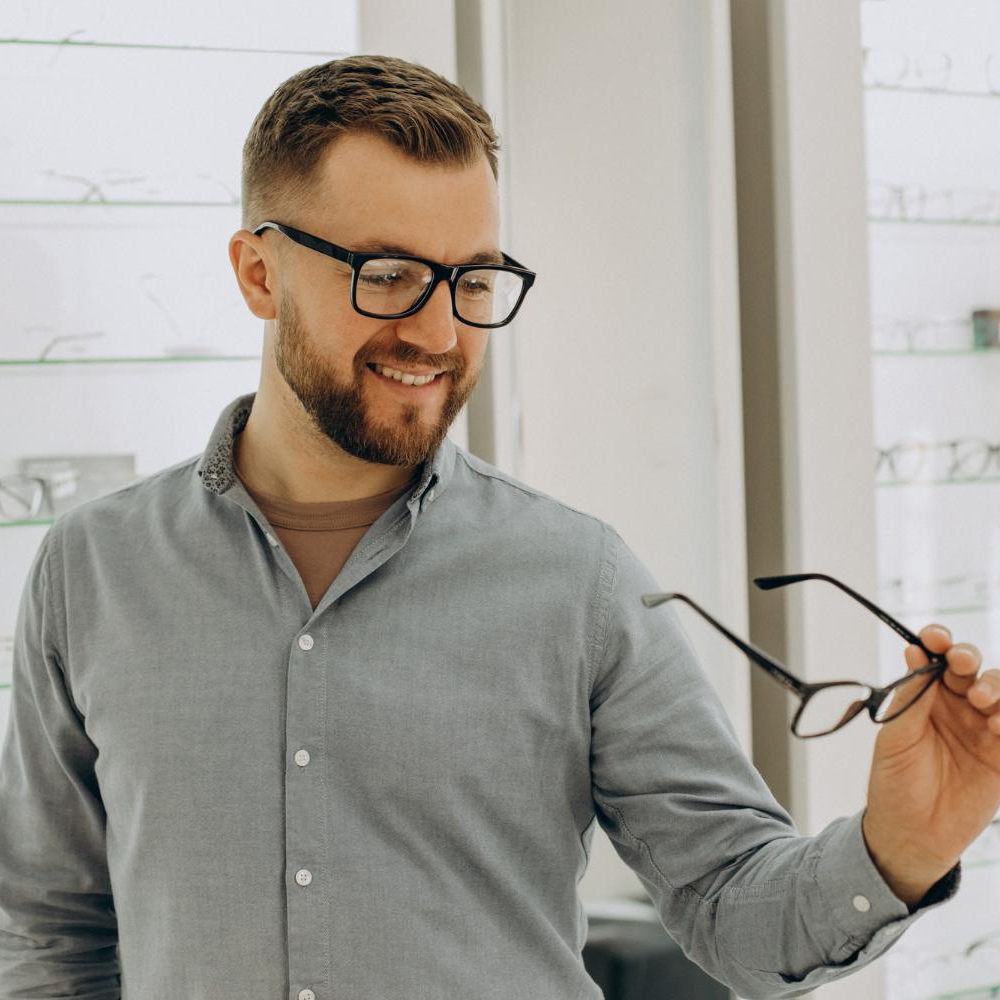 Homem experimentando óculos de grau em uma óptica após saber quanto tempo vale uma receita de óculos.