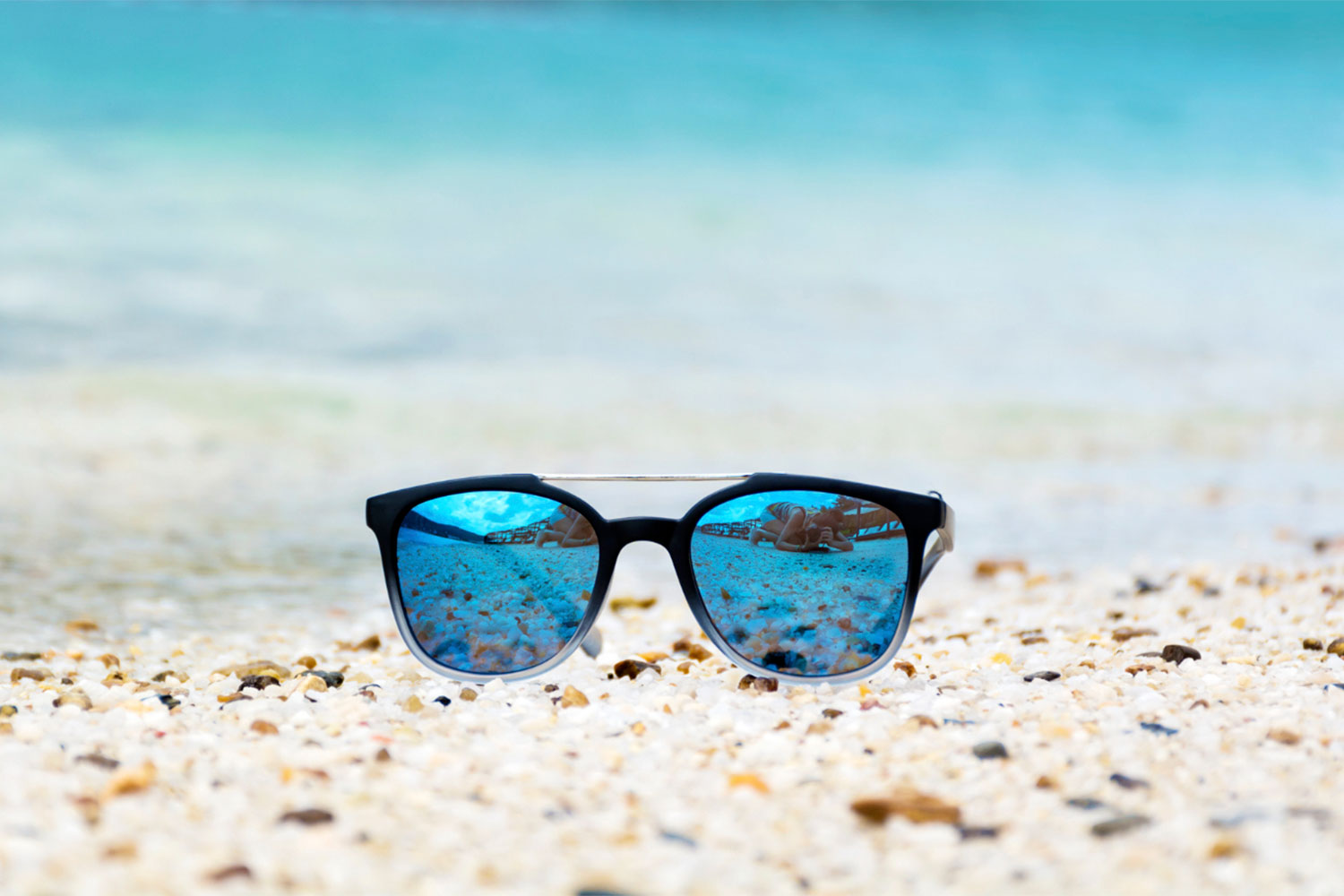 Óculos polarizados na areia de uma praia.